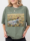 Woman wearing an oversized moss green t shirt with I’ll be in my office text and a soft vintage painting of a girl reading in a floral meadow