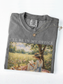 Folded pepper t shirt with I’ll be in my office text and a soft vintage painting of a woman reading under a tree in a floral meadow