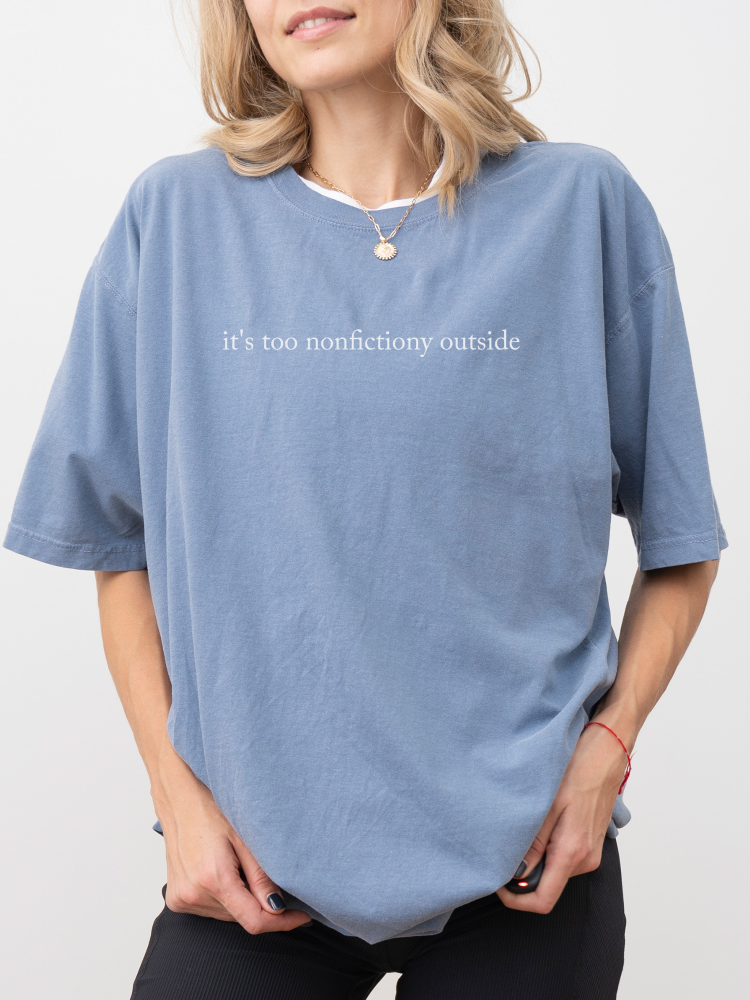 Woman wearing blue jean Comfort Colors book lover shirt that reads it's too nonfictiony outside styled casually with necklace and relaxed fit tee