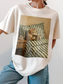 Ivory colored t-shirt with a vintage inspired illustration of a cat reading a book in bed next to a bedside table and tea cup. Styled casually with denim, creating a cozy and minimal book lover outfit perfect for everyday wear.
