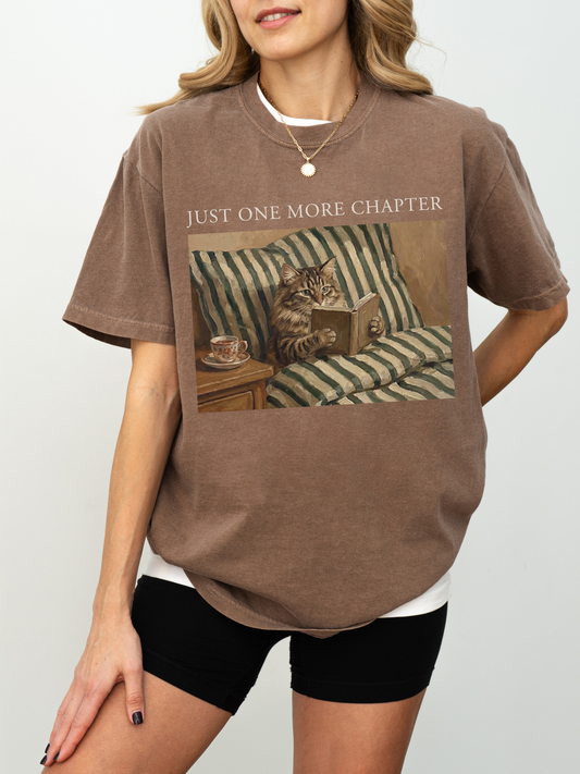 Woman modeling a espresso t shirt with just one more chapter text and a cozy vintage cat reading a book illustration on a striped couch