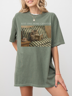 Person wearing a moss t-shirt with a cat reading a book graphic and 'Just One More Chapter' text.