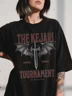 Close-up of a woman wearing a black Kejari Tournament fantasy graphic tee featuring distressed text and dragon-winged sword artwork inspired by the House of Night series by Carissa Broadbent. Bold red and gray typography adds a vintage battle aesthetic.