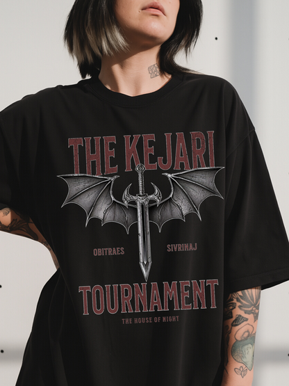 Close-up of a woman wearing a black Kejari Tournament fantasy graphic tee featuring distressed text and dragon-winged sword artwork inspired by the House of Night series by Carissa Broadbent. Bold red and gray typography adds a vintage battle aesthetic.