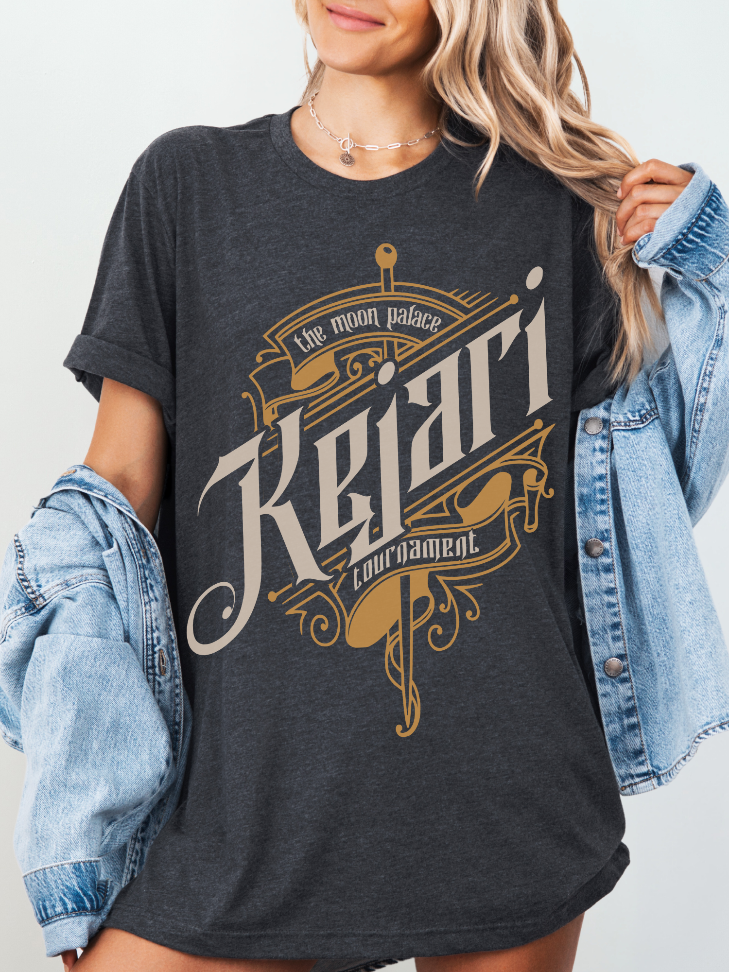 Dark grey T-shirt featuring bold sword and scroll design from The Moon Palace Kejari Tournament, officially licensed Carissa Broadbent fantasy merch.
