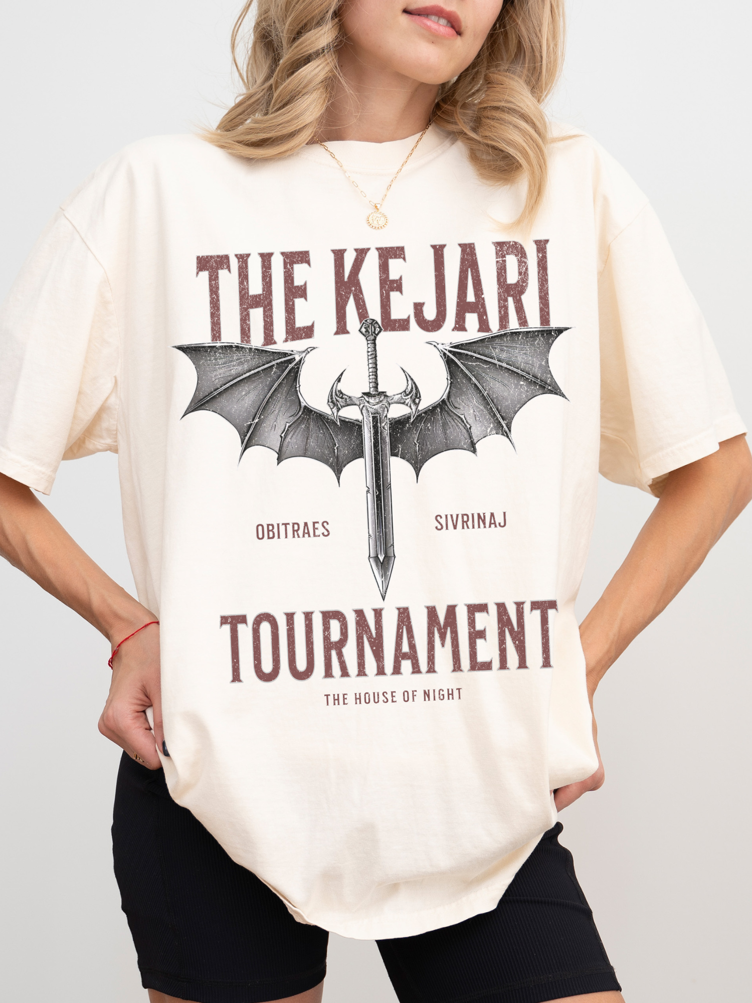 natural colored fantasy shirt with Kejari Tournament battle graphic inspired by the Serpent and the Wings of Night, modeled with a casual book lover aesthetic.