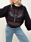 Woman posing in black Kejari Tournament sweatshirt with fantasy sword and wings print, paired with light blue jeans and gold necklace