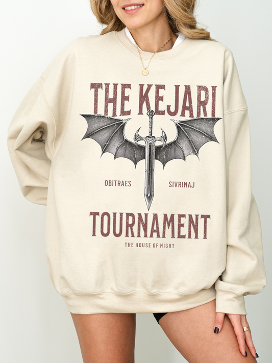 Model wearing Sand Kejari Tournament sweatshirt with sword and wings design, smiling and standing against a white wall