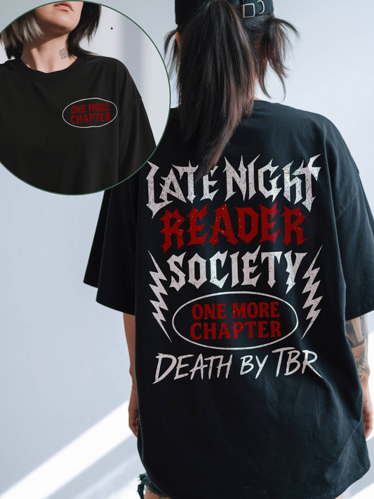 Woman wearing a black oversized t-shirt with distressed red and white metal-style text reading “Late Night Reader Society” and “Death by TBR” on the back, plus a red “One More Chapter” oval graphic. A close-up inset shows the same red oval detail printed on the front left chest. Perfect for book lovers and fantasy readers.