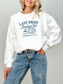 woman wearing a white sweatshirt that says late night reading club members only with books and a steaming mug graphic
