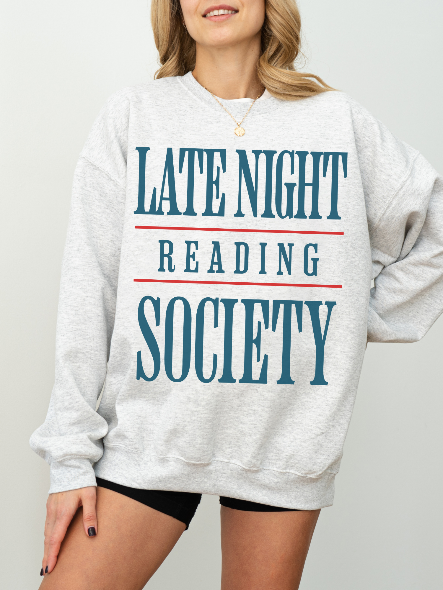 woman in an ash grey sweatshirt with teal blue and red graphic text reading late night reading society