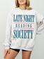 woman in an ash grey sweatshirt with teal blue and red graphic text reading late night reading society