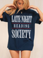 woman wearing a navy oversized tee that says late night reading society in white bold font with red underline