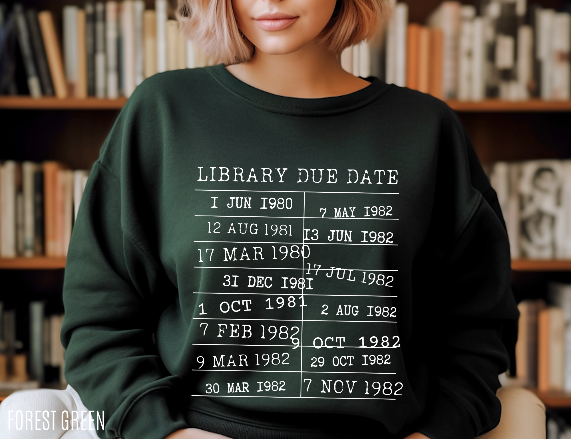 woman wearing forest green sweatshirt in library setting with white vintage library due date print