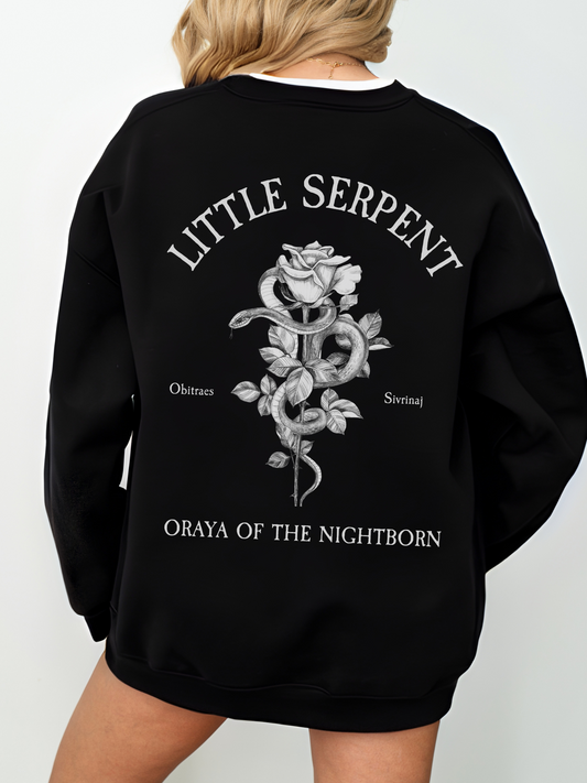Woman wearing black Gildan sweatshirt with Little Serpent design on the back, featuring a detailed rose and snake illustration, text reads Oraya of the Nightborn, officially licensed Crowns of Nyaxia merch
