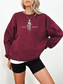 Maroon red Gildan sweatshirt worn by model, with centered Little Serpent fantasy rose and serpent design from The Serpent and the Wings of Night
