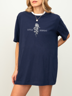 Navy Bella Canvas shirt featuring a centered fantasy design with the words Little Serpent on either side of a coiled snake and rose graphic, inspired by the Crowns of Nyaxia book series by Carissa Broadbent.