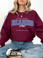 Maroon crewneck sweatshirt with bold “Late Night Reading Crew” text and stars, worn by woman sitting cross-legged in jeans
