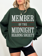 woman wearing a forest green sweatshirt with member of the midnight reading society in large white and red print