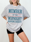 woman wearing a athletic heather grey t-shirt that says member of the midnight reading society in teal blue and red graphic text