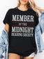 woman wearing a black t-shirt that says member of the midnight reading society in white and red block letters