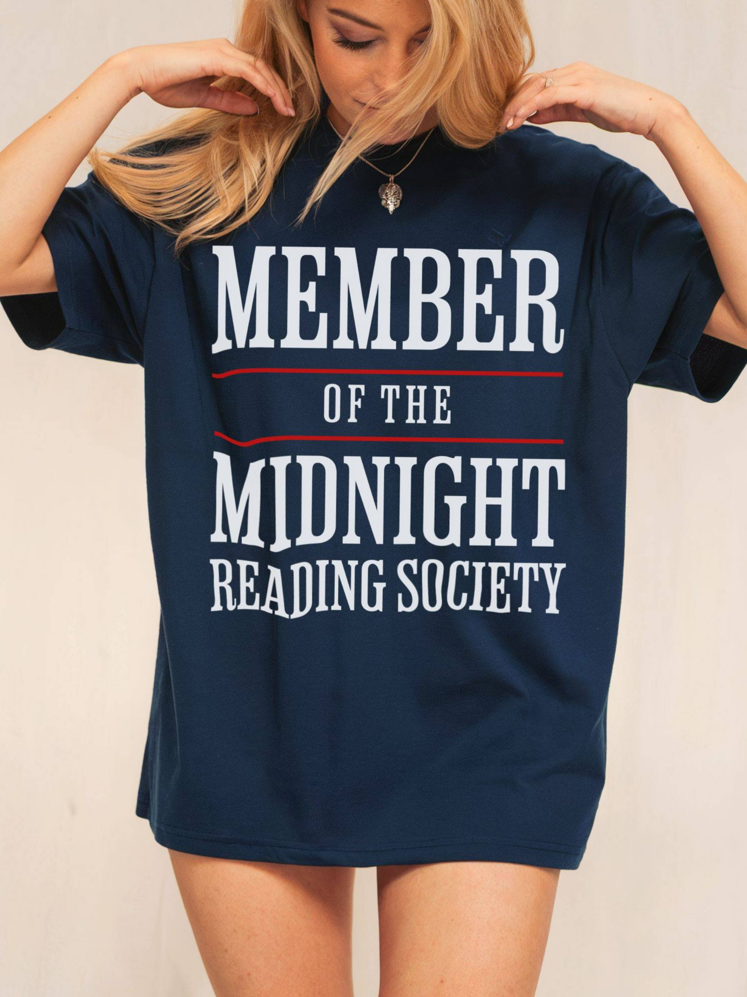 woman wearing a navy tee that says member of the midnight reading society in white text with bold red lines
