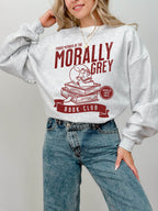 woman wearing ash grey sweatshirt with red morally grey book club design featuring skull and stacked books