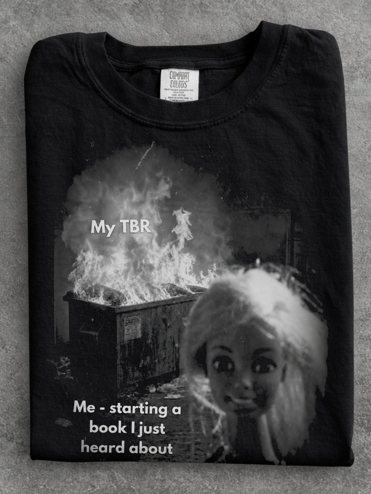 Black Comfort Colors shirt close up featuring a funny My TBR meme with a burning pile and Me starting a book I just heard about text, humorous reading shirt for bookworms and readers with an endless TBR