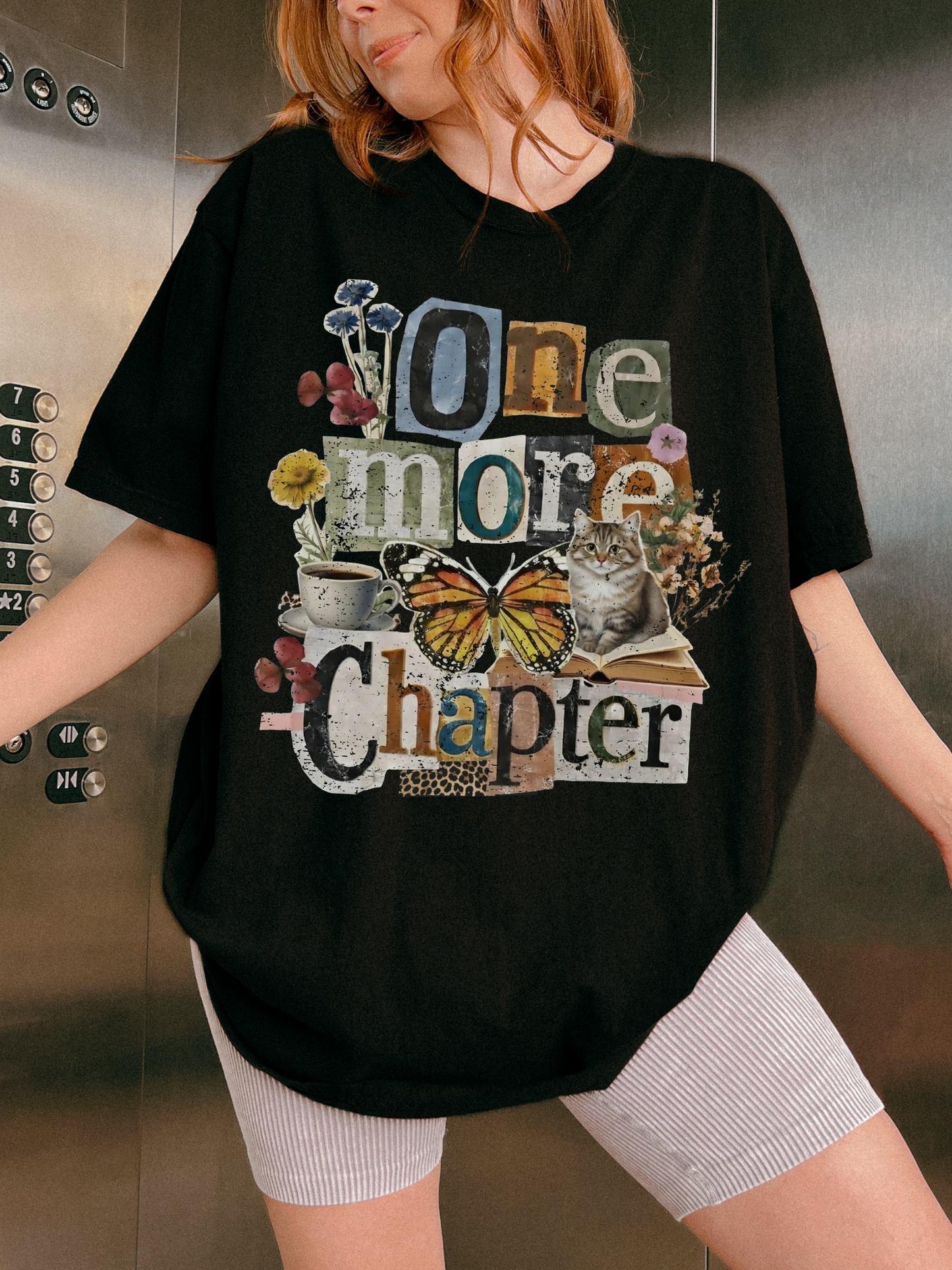 A woman wearing an oversized black graphic t-shirt with the text 'One more Chapter' in a collage style featuring a butterfly, cat, and flowers, paired with white ribbed shorts.