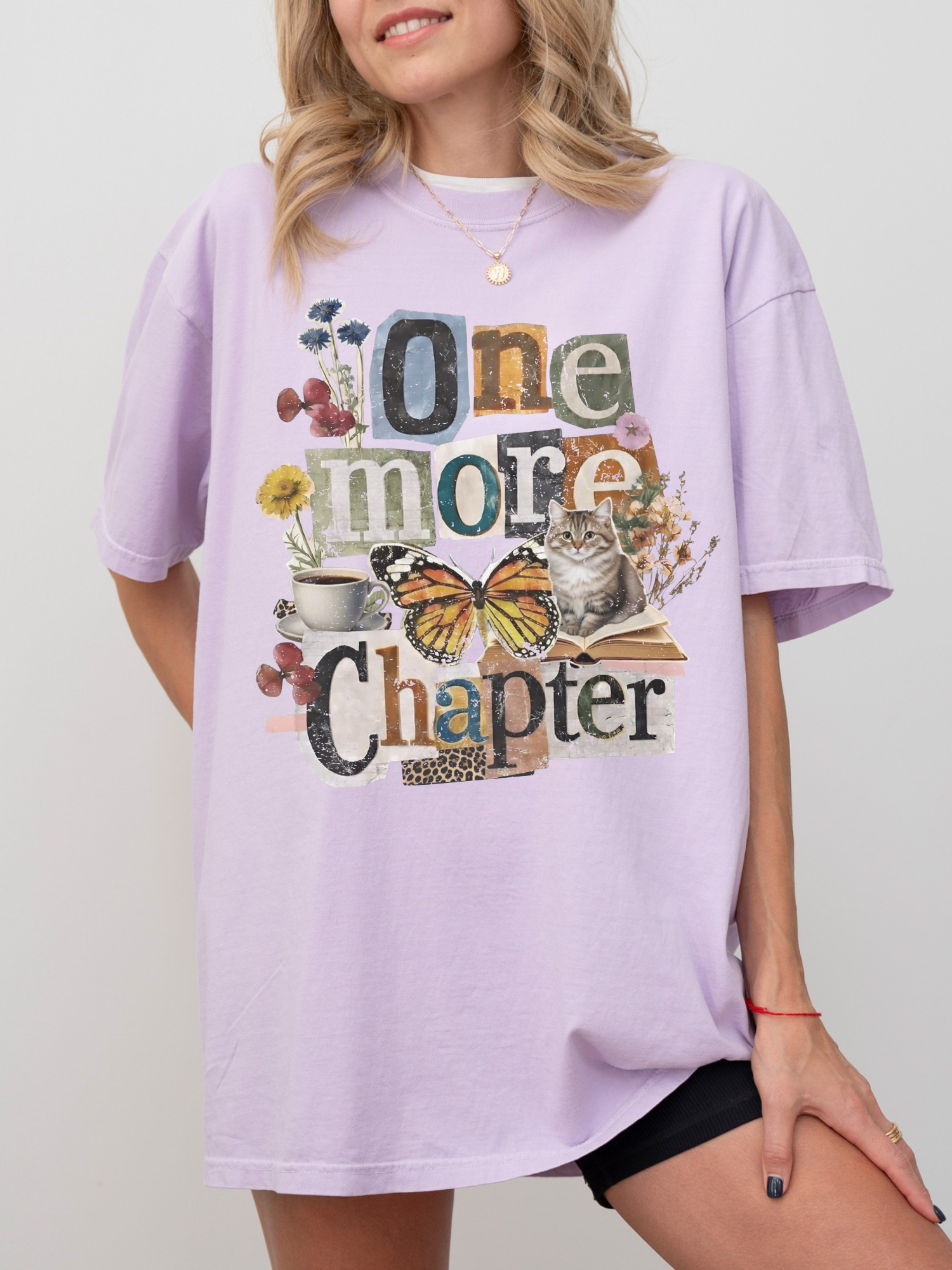 A woman wearing an oversized orchid t-shirt with a colorful graphic that reads 'One more Chapter' decorated with butterflies, flowers, and a cat.