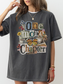 A woman wearing an oversized pepper graphic T-shirt with the phrase 'One more Chapter' in mixed typography, decorated with flowers, a butterfly, a cat, and books.