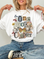 A woman wearing a white graphic t-shirt with a vintage-style collage print that reads 'One more Chapter' with a butterfly, cat, flowers, and coffee cup. She is wearing blue jeans and a black and white sneaker, sitting against a light gray background.
