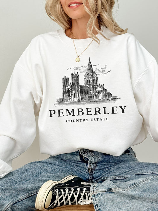 woman sitting in white sweatshirt with vintage line art of Pemberley estate and sneakers