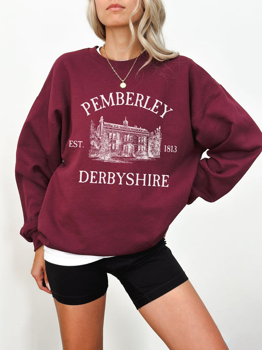 woman wearing maroon sweatshirt with large vintage Pemberley estate print and white lettering