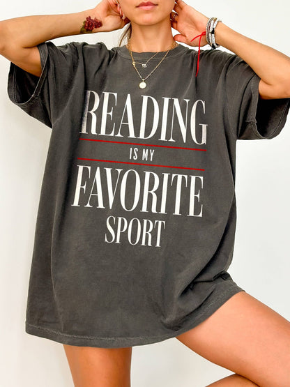 Person wearing a gray t-shirt with 'Reading is my favorite sport' text.