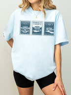 woman wearing light blue t shirt with vintage stamp illustrations of Longbourn House Pemberley House and Netherfield Park classic literature inspired apparel