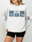 woman wearing grey sweatshirt featuring vintage stamp design of Longbourn House Pemberley House and Netherfield Park from Pride and Prejudice
