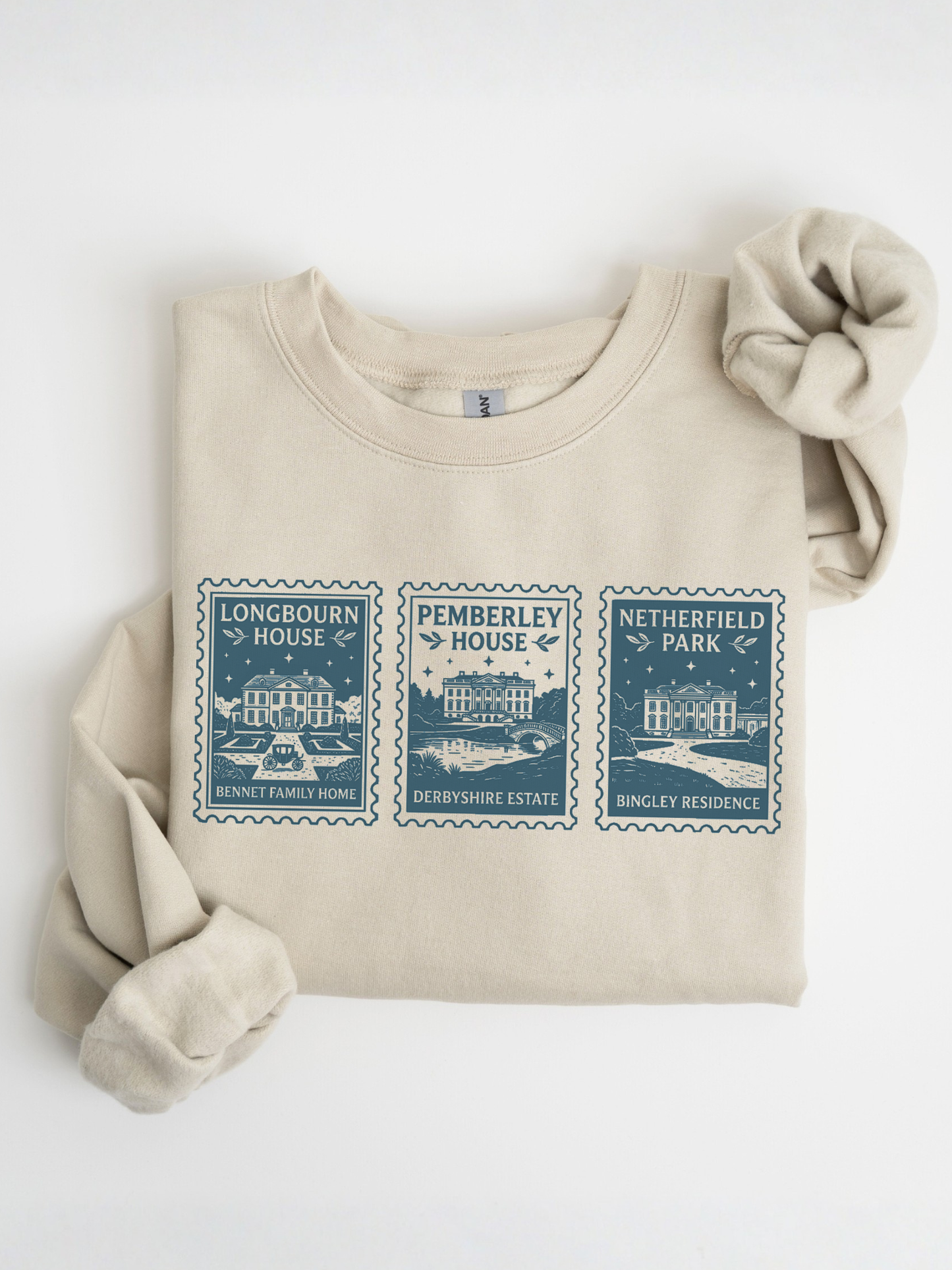 folded sand sweatshirt with Pride and Prejudice stamp illustration showing Longbourn House Pemberley House and Netherfield Park classic literature design