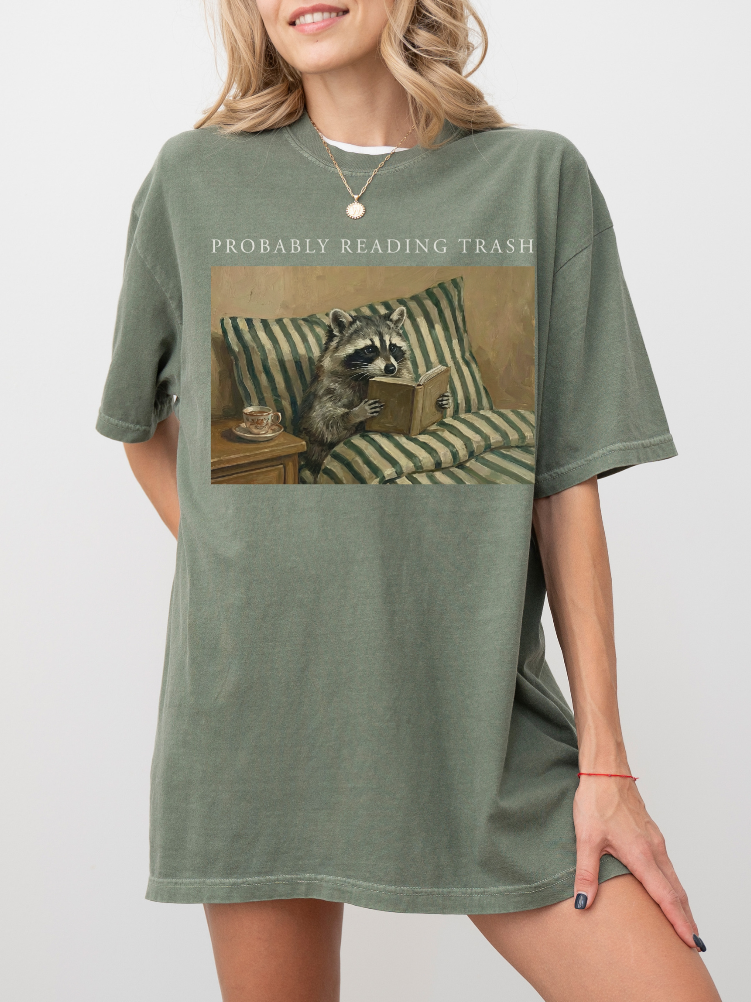 woman wearing oversized moss shirt with probably reading trash raccoon reading book illustration cozy relaxed fit book lover outfit