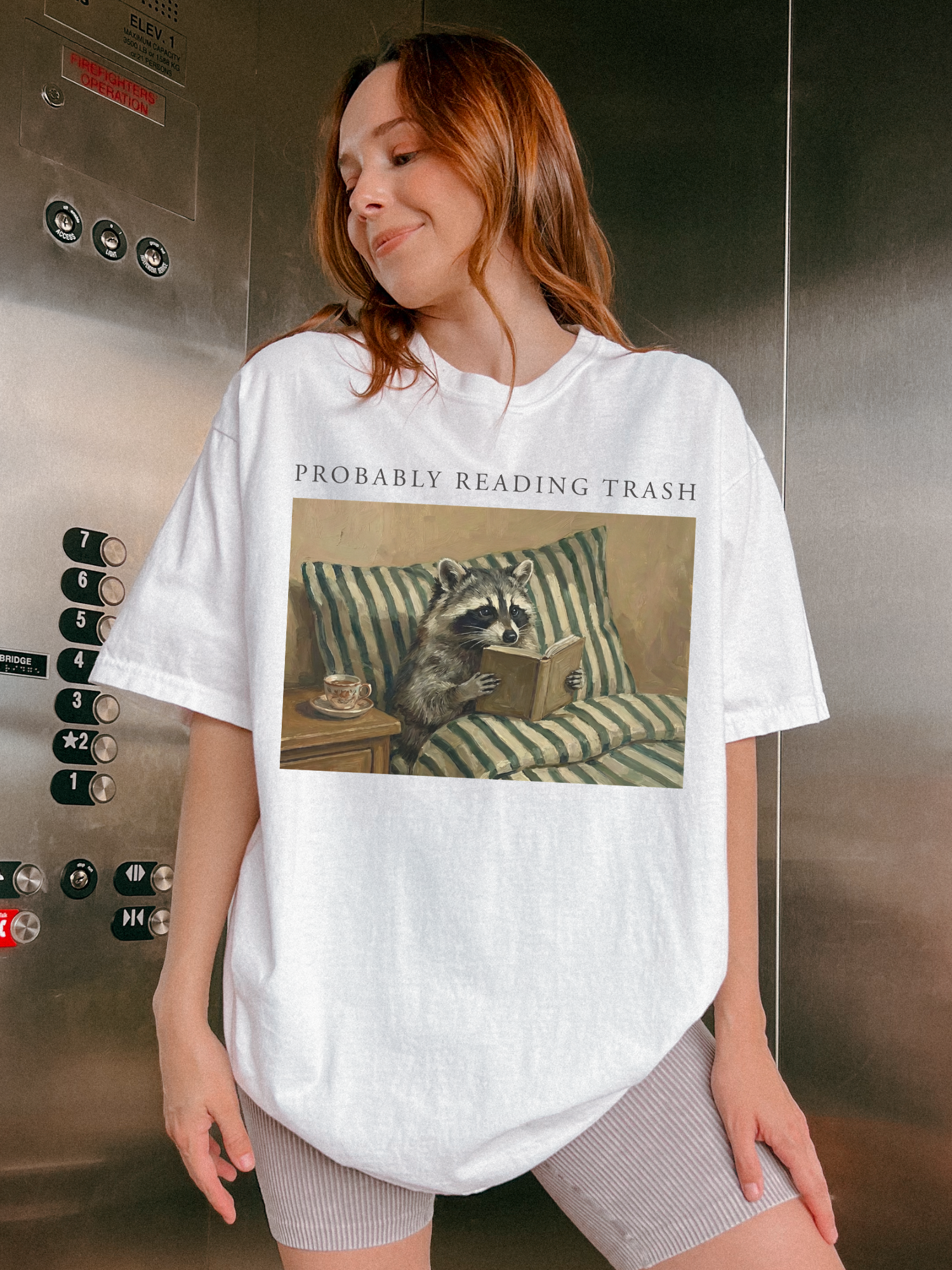 woman wearing white probably reading trash raccoon reading book shirt standing in elevator casual lifestyle photo book lover aesthetic outfit