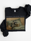 folded black sweatshirt with probably reading trash text and vintage raccoon reading a book on couch illustration cozy book lover aesthetic