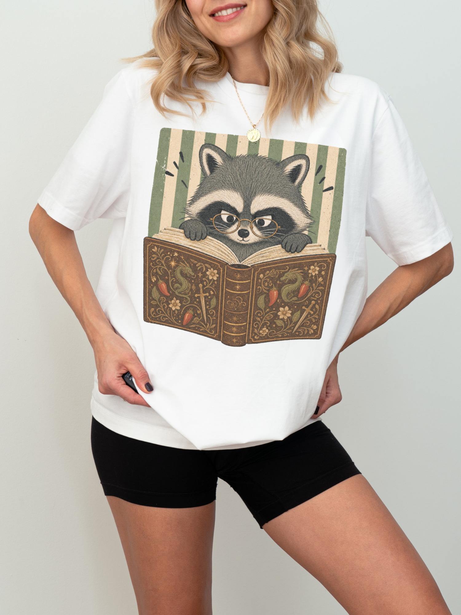 woman wearing white raccoon reading book t-shirt with vintage bookish raccoon and fantasy book illustration