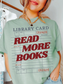 woman wearing a bay Comfort Colors shirt featuring a vintage library card graphic with the phrase read more books in bold red lettering, styled with layered gold necklaces and casual denim for a cozy book lover aesthetic