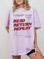 woman wearing an orchid Comfort Colors shirt featuring a retro library card graphic with read return repeat text in bold red letters, oversized book lover tee styled with biker shorts and gold jewelry