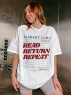 woman wearing a white Comfort Colors shirt featuring a vintage library card read return repeat design in an elevator setting, oversized reader graphic tee perfect for librarians bookworms and reading enthusiasts