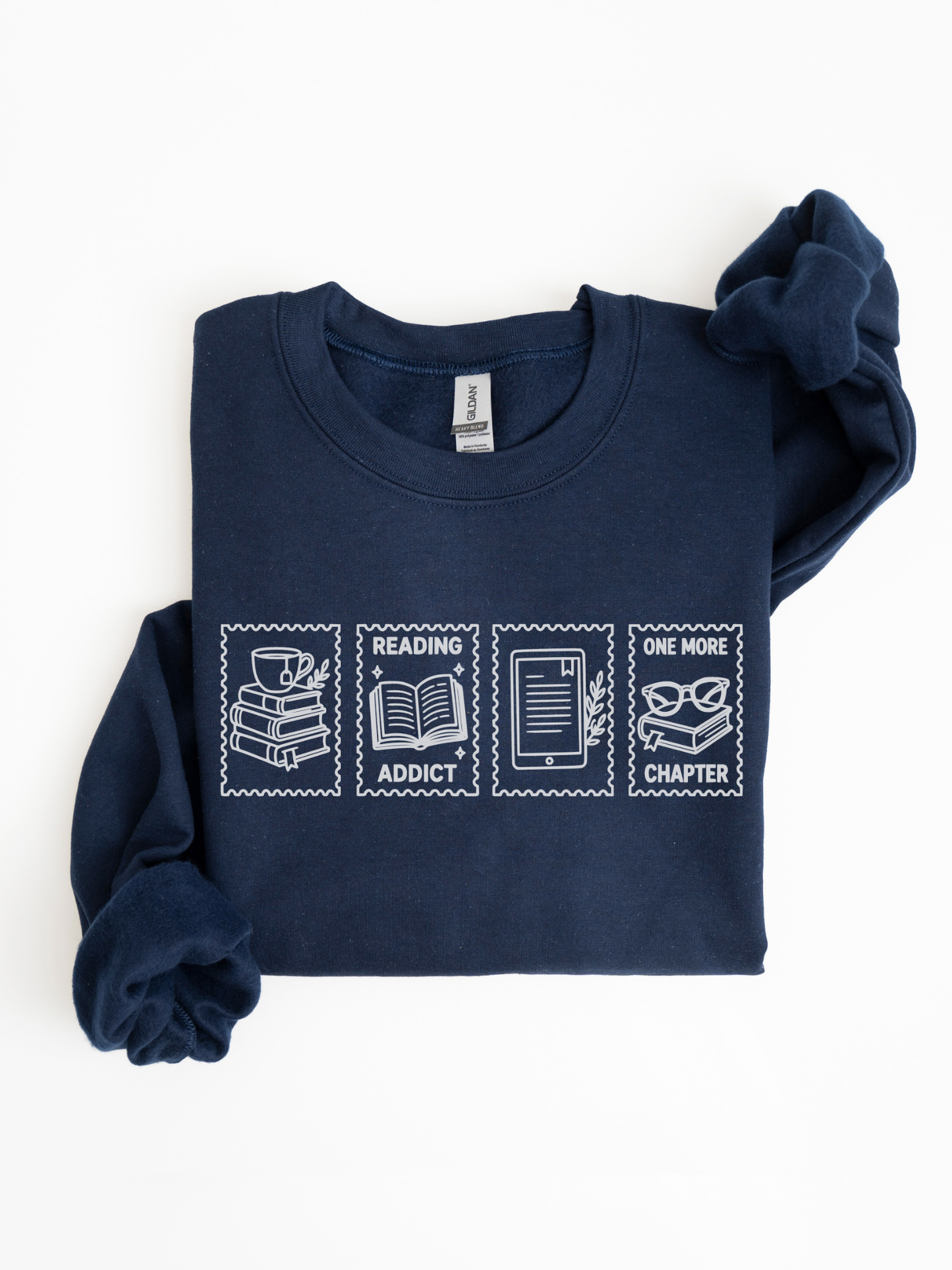 folded navy blue sweatshirt featuring reading addict one more chapter postage stamp design with book stack coffee mug open book e reader and reading glasses artwork for readers