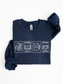 folded navy blue sweatshirt featuring reading addict one more chapter postage stamp design with book stack coffee mug open book e reader and reading glasses artwork for readers