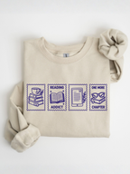 folded sand sweatshirt featuring reading addict one more chapter postage stamp style design with stack of books coffee cup open book e reader and reading glasses artwork