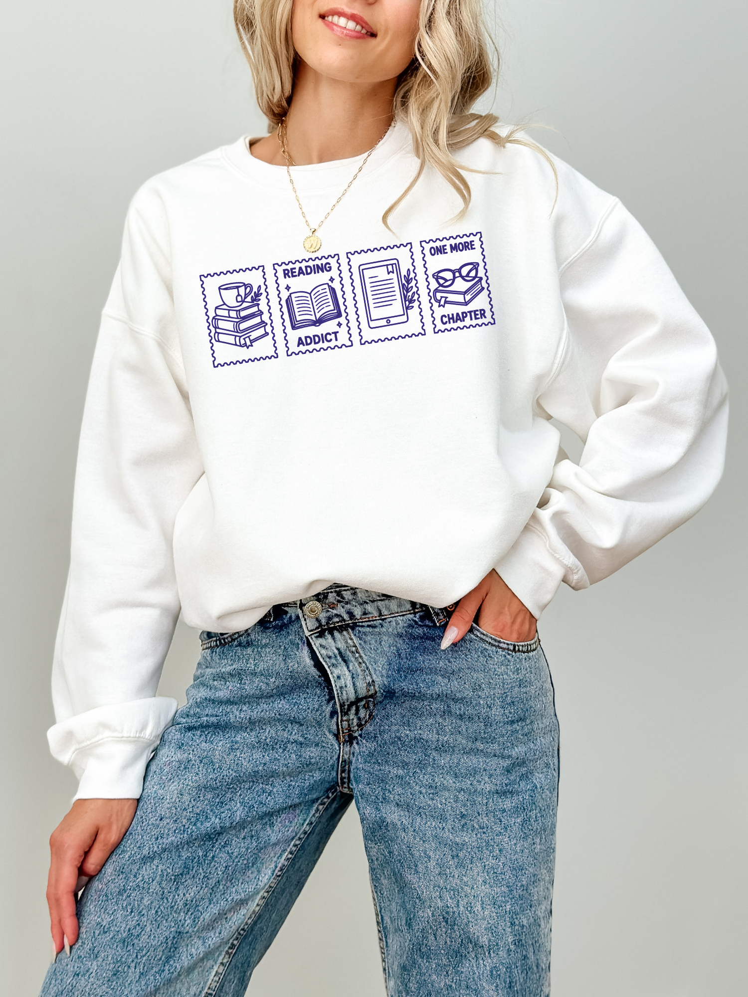 woman wearing a white sweatshirt featuring reading addict one more chapter postage stamp style design with books coffee open book e reader and reading glasses illustrations for book lovers