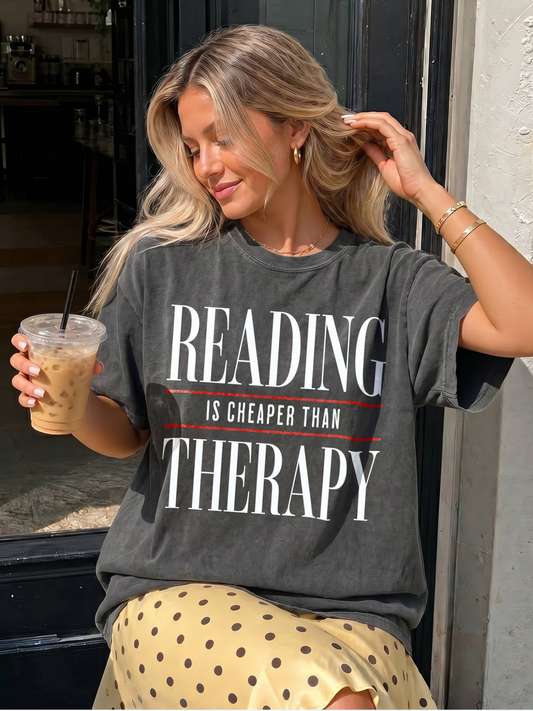 Woman wearing a t-shirt with 'Reading is cheaper than therapy' text, holding a drink.
